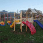 Estación de juegos de madera modelo Las Cabras con columpios de seguridad y muro rojo