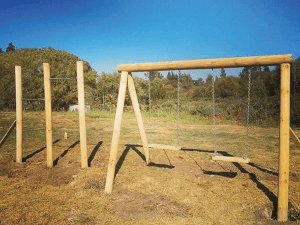 Plaza de juegos de madera San Fernando con columpios y barras de ejercicios