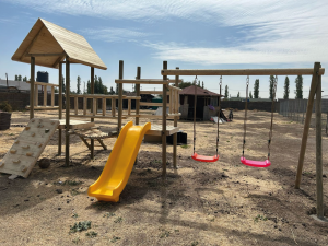 Plazas de juegos infantiles modelo Calera de Tango con puente de equilibrio, resbalín amarillo y columpios.