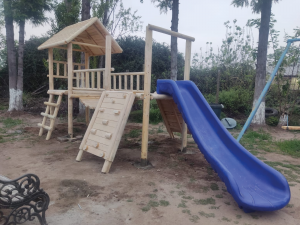 Juegos infantiles de madera modelo Linderos con resbalín azul y muro de escalada frontal.